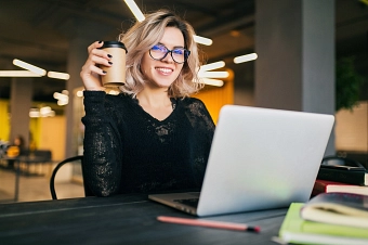 Blonde junge Frau am Laptop mit Kaffeebecher&nbsp;&copy;&nbsp;designed by Freepik
